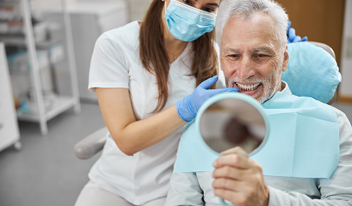 Image of a man looking at his smile after a dental implant placement, at United Smile Centres in Louisville, KY.