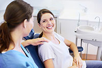 Smiling woman sitting in a chair, going over patient information with the dental profesional, at United Smile Centres in Louisville, KY.