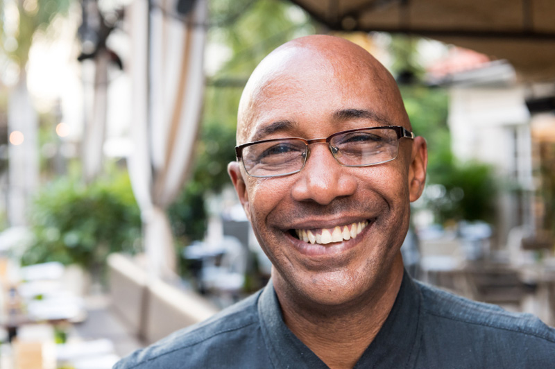 Mid age male with glasses smiling at the camera.