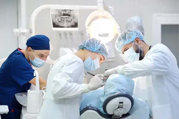 A team of dentists and oral surgeons performing Chao Pinhole gum surgery on a patient in a well-equipped surgical setting.